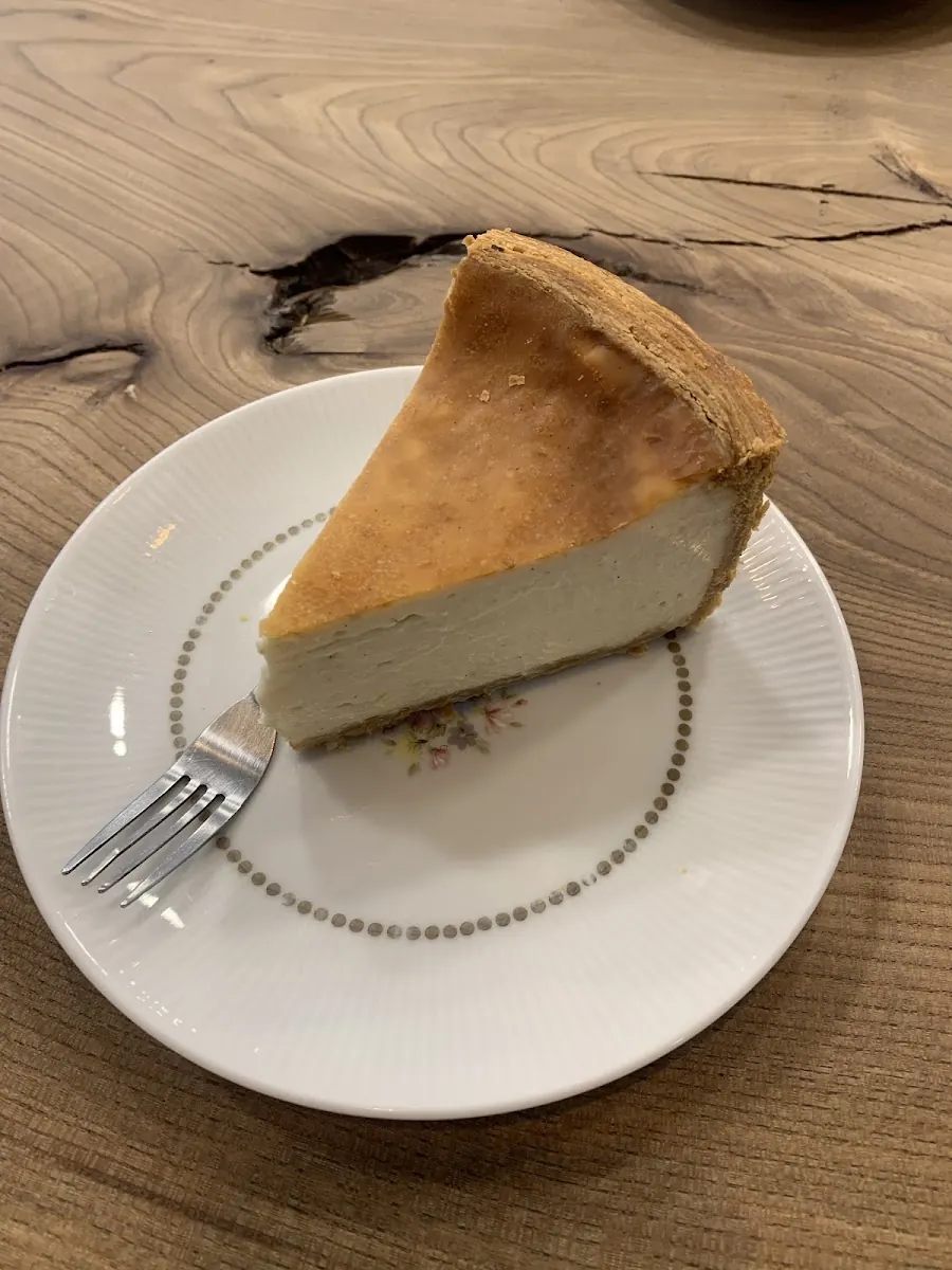 Une part de cheesecake servie à l'assiette sur la grande table en bois