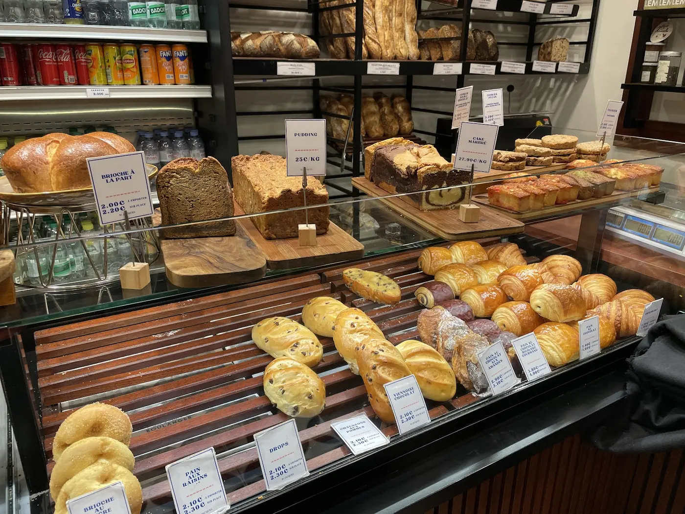 La vitrine de M. Jacques, pains, brioches et viennoiseries alignés sur les grilles